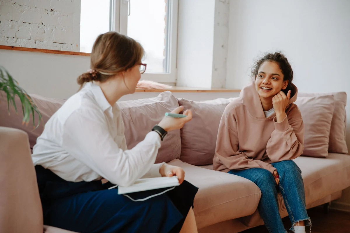 A counselor and a young woman talking on a sofa