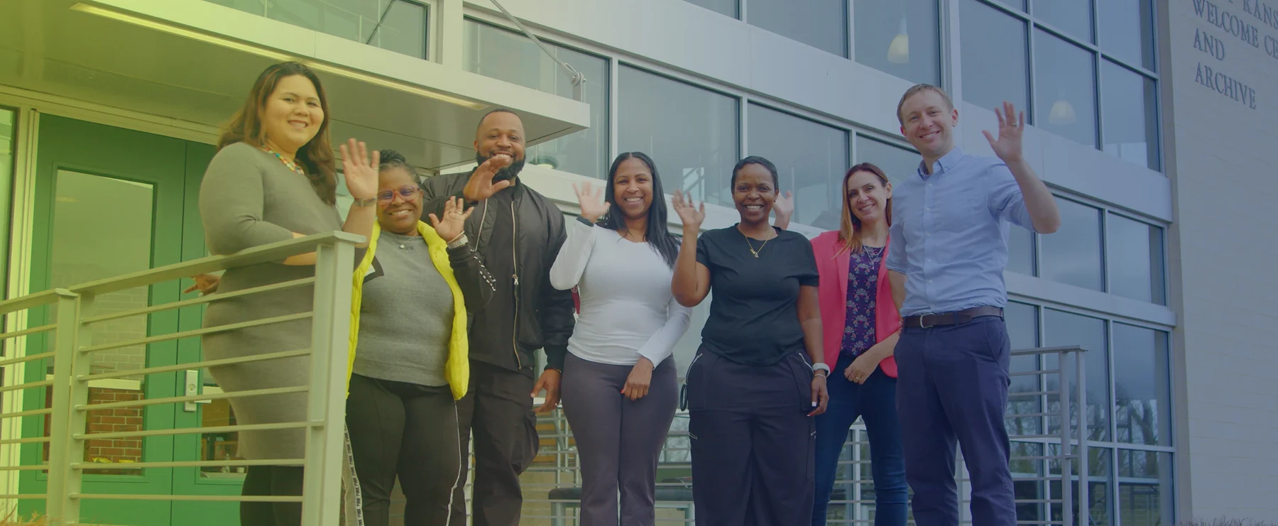 Everstand staff members waving from the front steps of a campus building